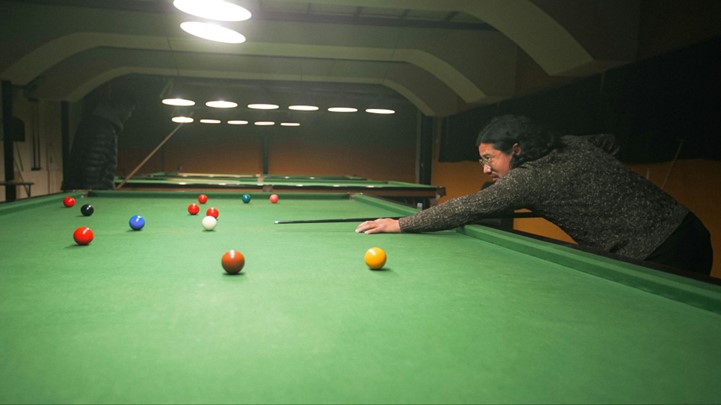 Un homme s’apprête à tirer la blanche sur une table de snooker